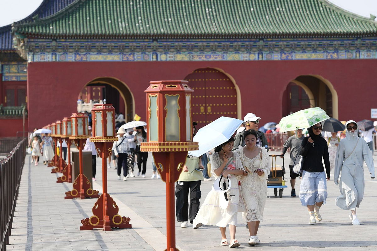 Tourists shield themselves from the sunshine with umbrellas at the Temple of Heaven in Beijing, capital of China, June 23, 2023.