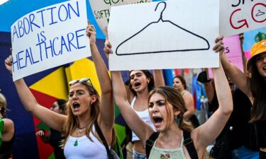 Abortion rights activists hold signs reading "Abortion is Healthcare" as they rally in Miami