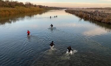 Immigrants wade across the Rio Grande while crossing Sunday from Mexico to Eagle Pass