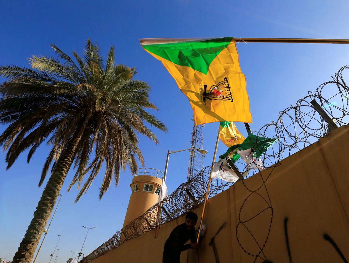 <i>Thaier al-Sudani/Reuters/File</i><br/>The Kataib Hezbollah militia group's flag flies at a protest outside the US Embassy in Baghdad