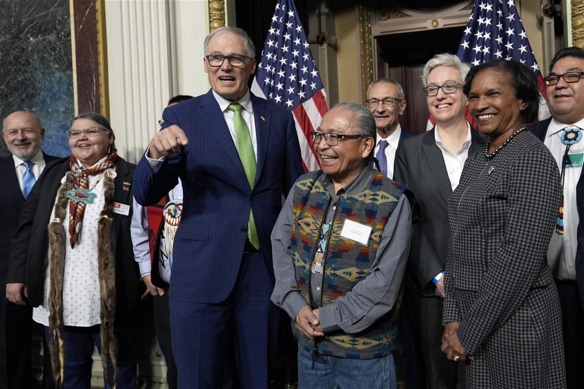 Washington Gov. Jay Inslee, third from left, stands with Chair Gerry Lewis of the Yakama Nation, fourth from left, as they and others pose for a photo following a ceremonial signing ceremony in Washington, Friday, Feb. 23, 2024. The ceremonial signing is an agreement between the Biden administration and state and Tribal governments to work together to protect salmon and other native fish, honor obligations to Tribal nations, and recognize the important services the Columbia River System provides to the economy of the Pacific Northwest.