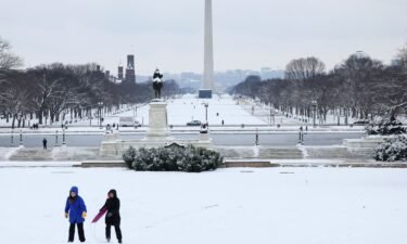 Pedestrians walk through snow and high winds on March 21
