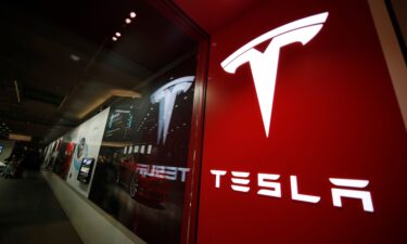 A sign bearing the Tesla company logo is displayed outside a Tesla store in Cherry Creek Mall in Denver