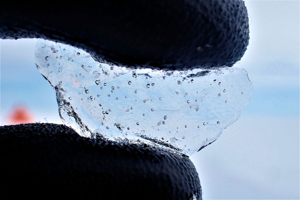 A scientist holds a piece of ice core drilled from West Antarctica, showing the air bubbles trapped within.