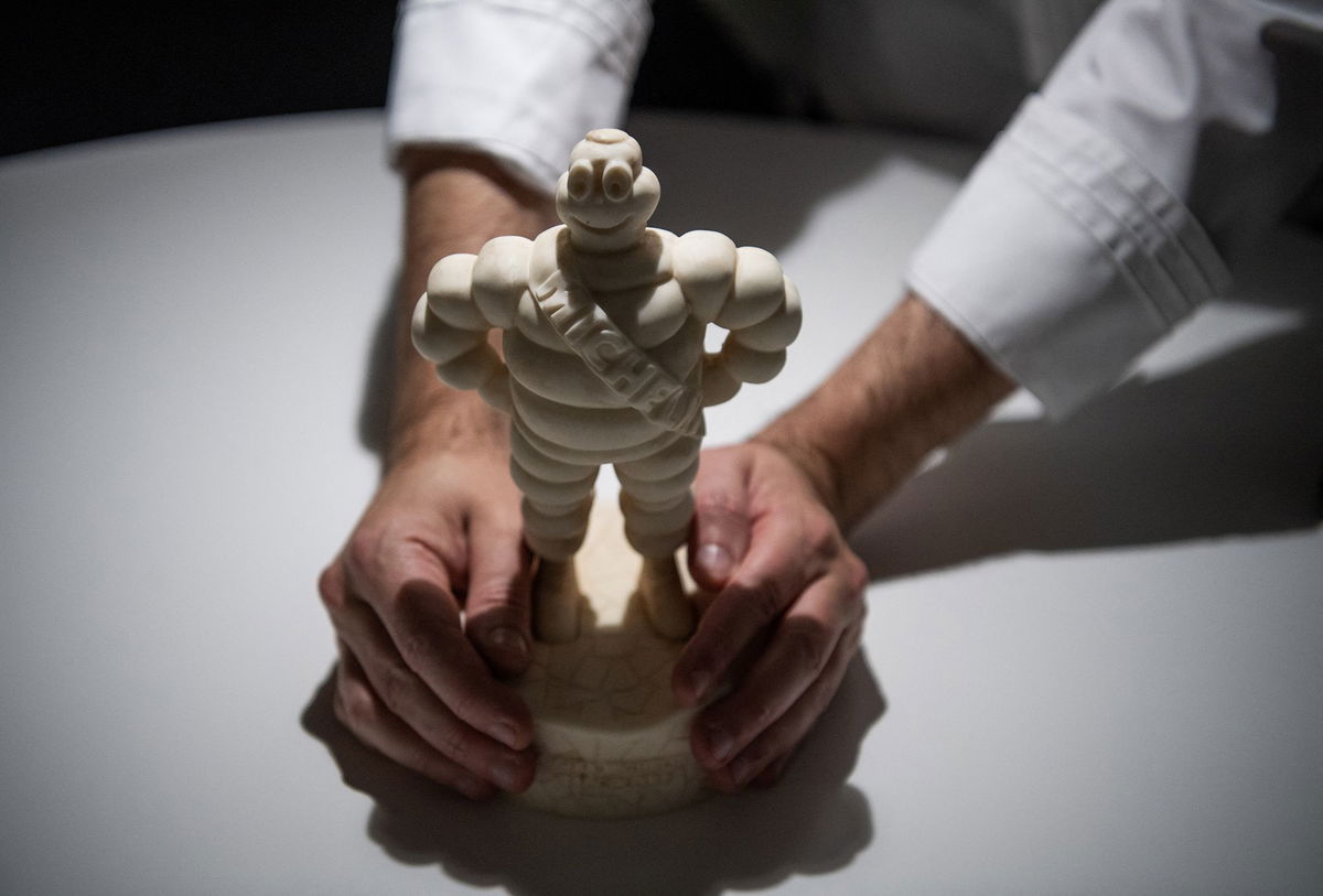 Spanish chef Paco Morales holds a figurine of Bibendum, commonly known as the Michelin Man, on November 30, 2023 at his restaurant NOOR in Cordoba, Spain, two days after receiving a third Michelin star.