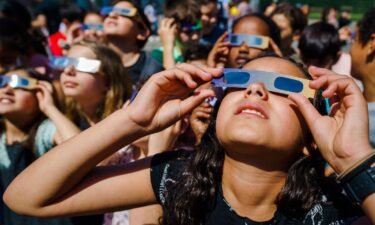 Students wear protective glasses to view a partial solar eclipse over Schiedam