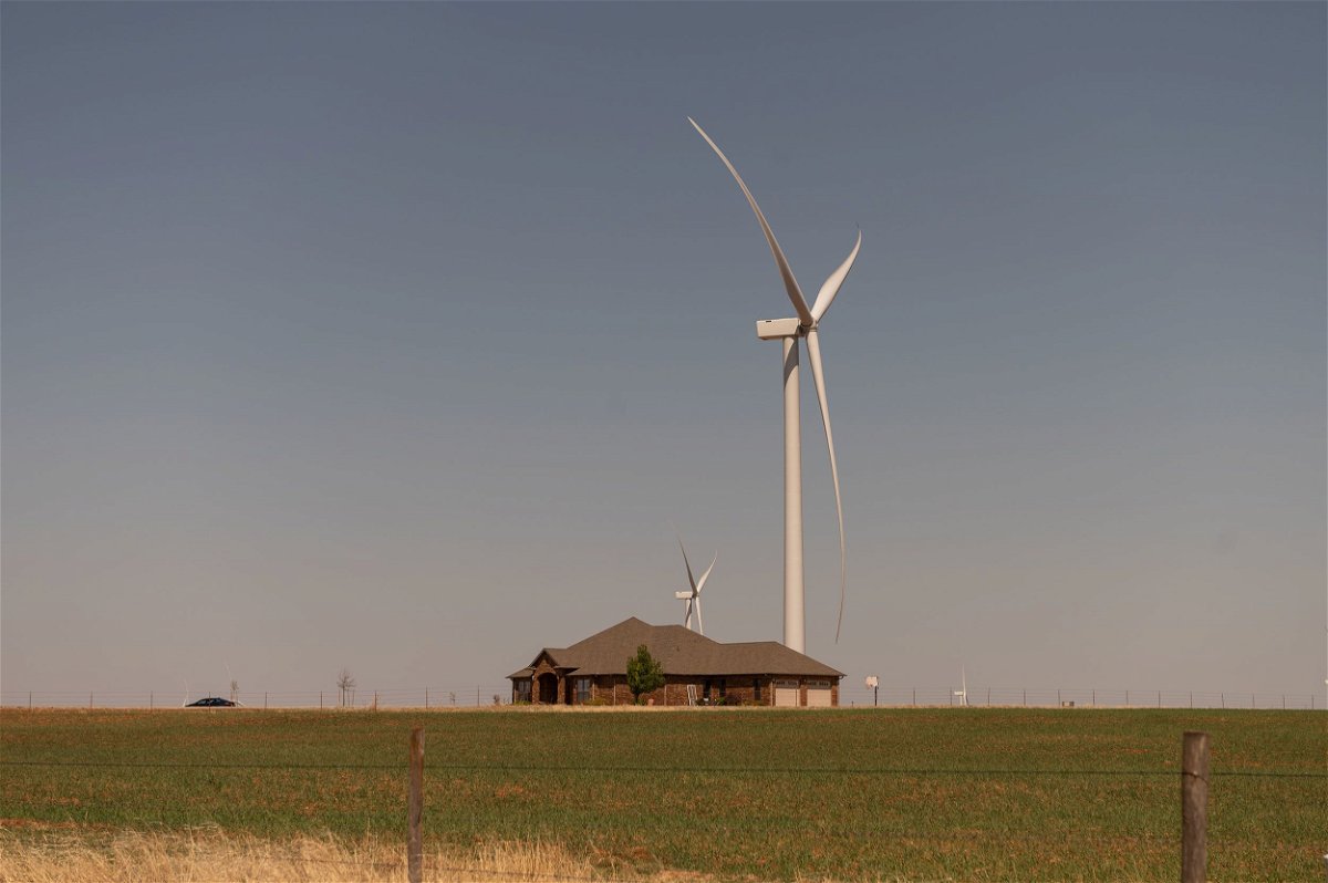 Wind turbines tower above a home in Weatherford, Oklahoma, in April 2022. As wind energy expands in the United States, concerns have grown about the potential for tall turbines to be a drag on property values.