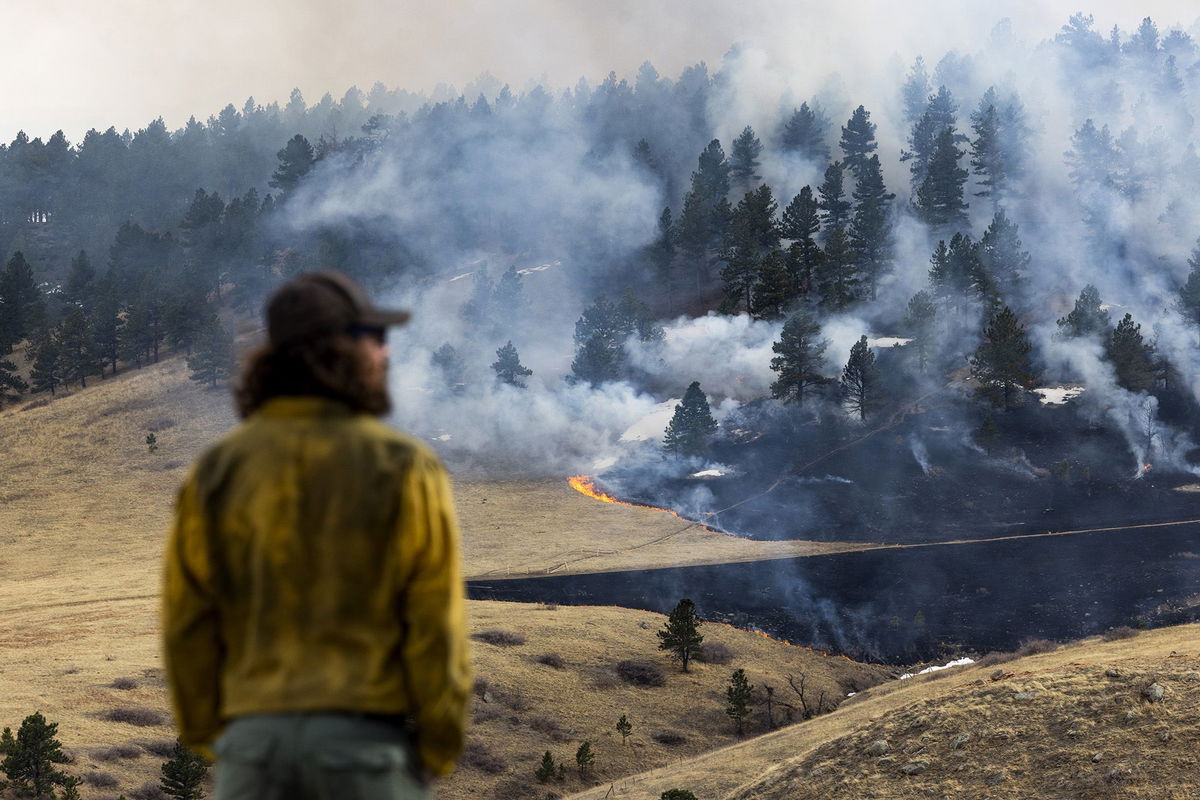 A firefighter watches as a fire burns through grass on March 26, 2022 in Boulder, Colorado.