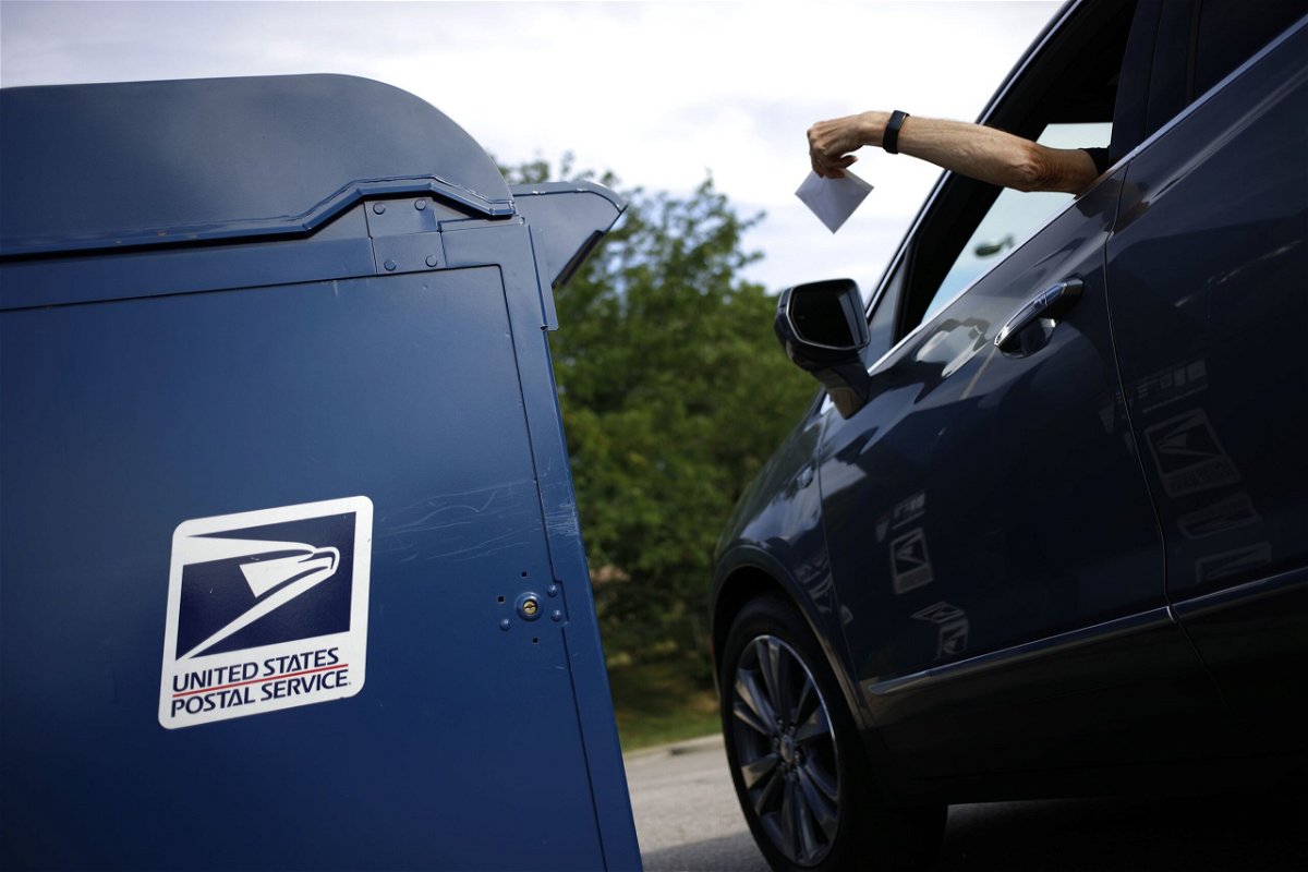 A motorist drops a letter into a USPS mail drop box at a post office in Kentucky in 2022.