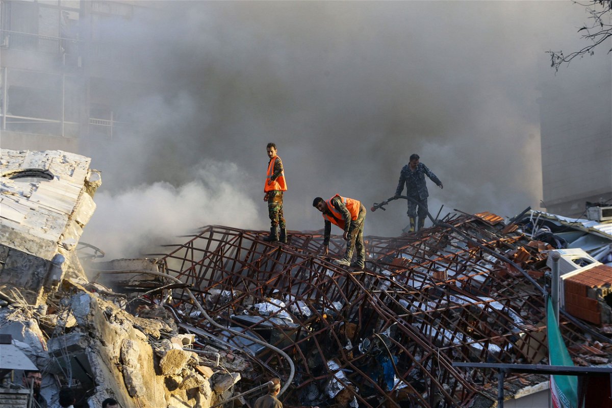 <i>Louai Beshara/AFP/Getty Images via CNN Newsource</i><br/>Emergency personnel extinguish a fire at the site of strikes which hit a building next to the Iranian embassy in Syria's capital Damascus on Monday