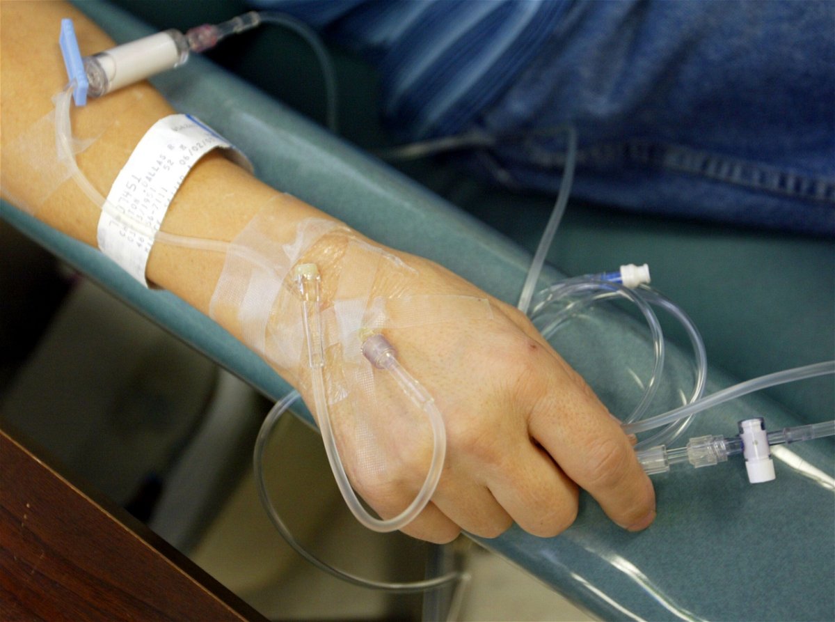 A cancer patient holds the IV tubes during chemotherapy.