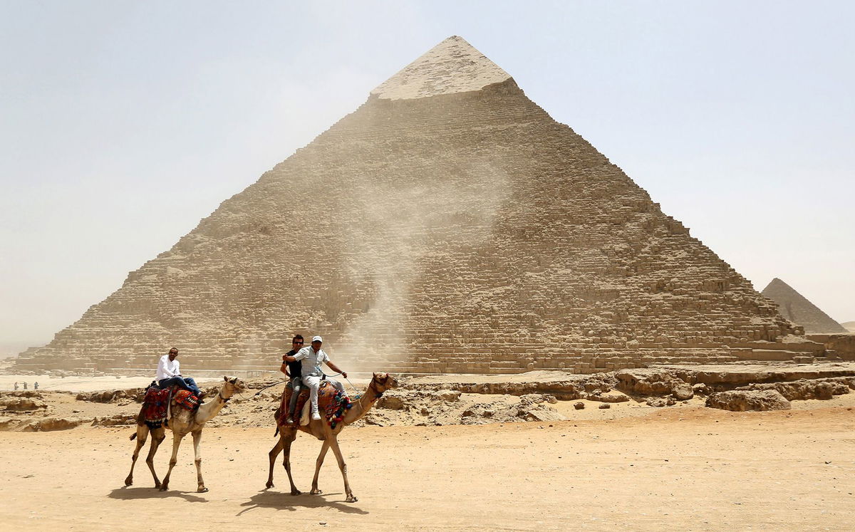 Tourists ride on camels next to the Pyramid of Khufu on the Great Pyramids of Giza, on the outskirts of Cairo, on April 27, 2015. A total eclipse will cross over the pyramids in 2027.