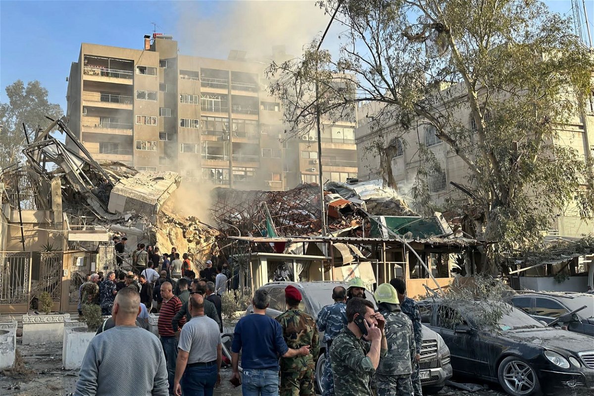 Emergency and security personnel gather at the site of strikes which hit a building next to the Iranian embassy in Syria's capital Damascus