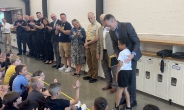 Superintendent Steve Wood congratulates second grader Trey Lewis for alerting others when a classmate had a severe allergic reaction to a granola bar.