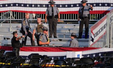 Law enforcement officers work at the campaign rally site for Republican presidential candidate former President Donald Trump is empty and littered with debris July 13