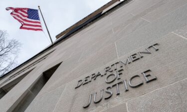 The US Ffag flies above a sign marking the US Department of Justice headquarters building on January 20