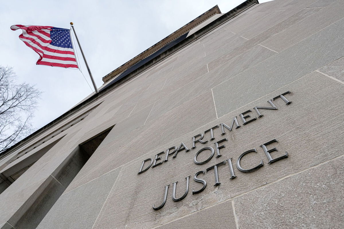 <i>J. David Ake/Getty Images via CNN Newsource</i><br/>The US Ffag flies above a sign marking the US Department of Justice headquarters building on January 20