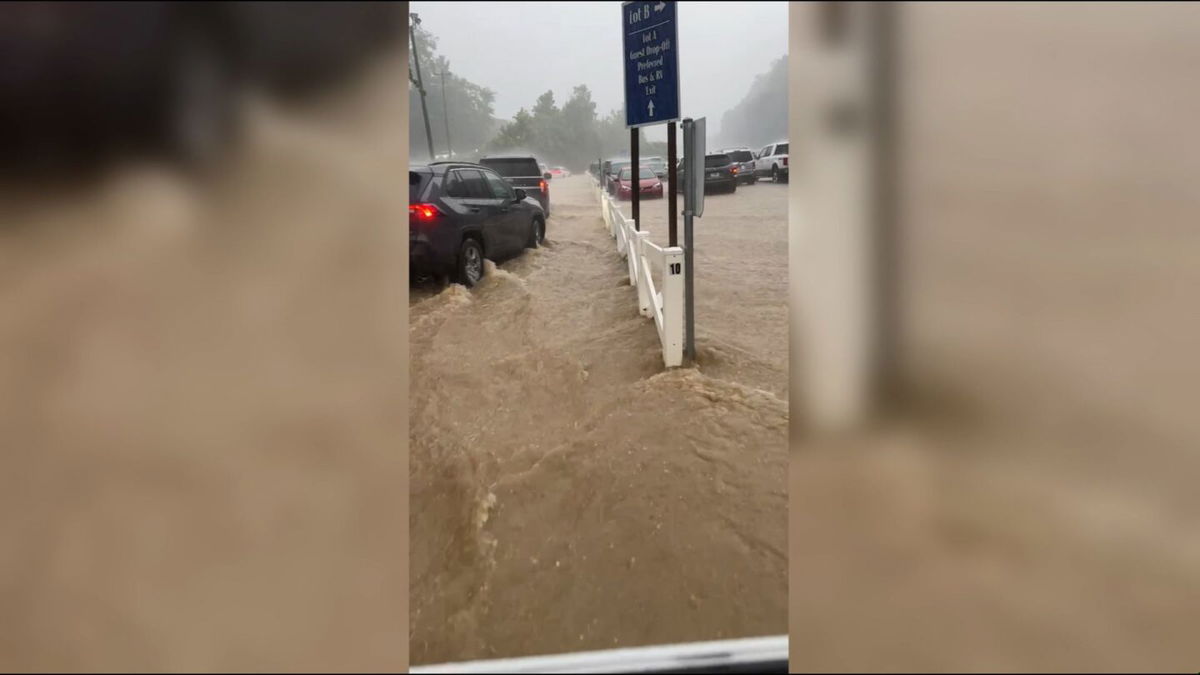 Part of Dollywood's parking lot can be seen flooded as cars try to exit the grounds, plowing water in their trek.