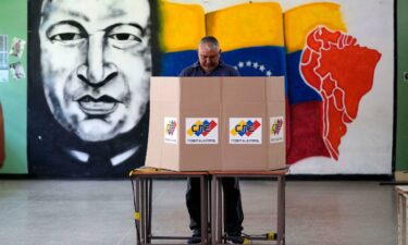 A voter chooses his candidate in front of a mural of late Venezuelan President Hugo Chavez during the presidential election in Caracas