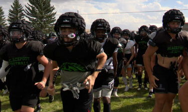 A large number of football players in black uniforms run towards the camera.