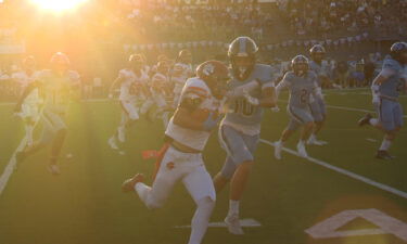 A Madison football player stiff-arms a Skyline defender as the sunset beams down overhead.