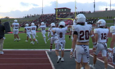 Rigby football players jog onto Highland's field prior to a game.