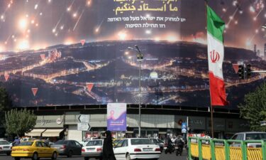 People walk on the streets of Tehran where Iranian flags and Hezbollah banners are seen