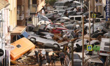 Damaged cars are seen along a road affected by torrential rains that caused flooding