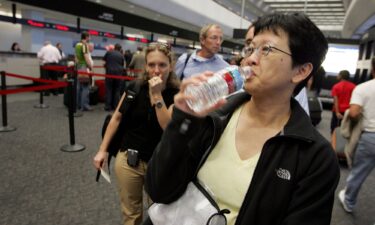 A passenger takes a sip of water before throwing away the bottle at a security checkpoint at San Francisco International Airport.