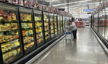 A lone shopper places items in her cart in the frozen food aisle of a Walmart store on November 14