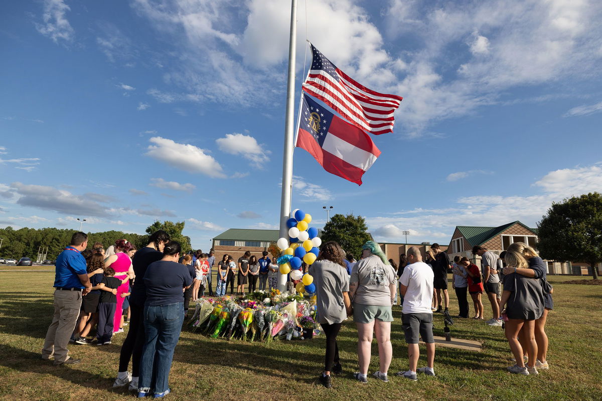 <i>Jessica McGowan/Getty Images via CNN Newsource</i><br/>Students and community members make a prayer circle around a makeshift memorial outside Apalachee High School in September 2024 in Winder