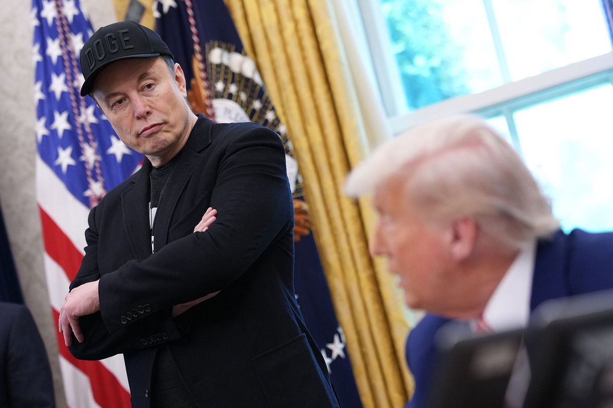 <i>Kevin Dietsch/Getty Images via CNN Newsource</i><br/>Tesla CEO Elon Musk listens as President Donald Trump speaks to reporters in the Oval Office of the White House on May 30