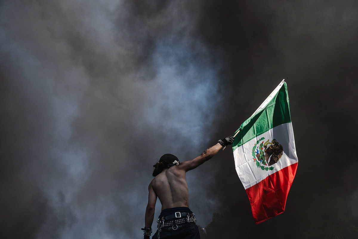 <i>Aude Guerrucci/Reuters via CNN Newsource</i><br/>A demonstrator waves a Mexican flag during a protest against federal immigration sweeps