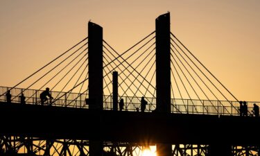Poeple walk across the Big Four Bridge as the sun sets at Waterfront Park on June 22 in Louisville