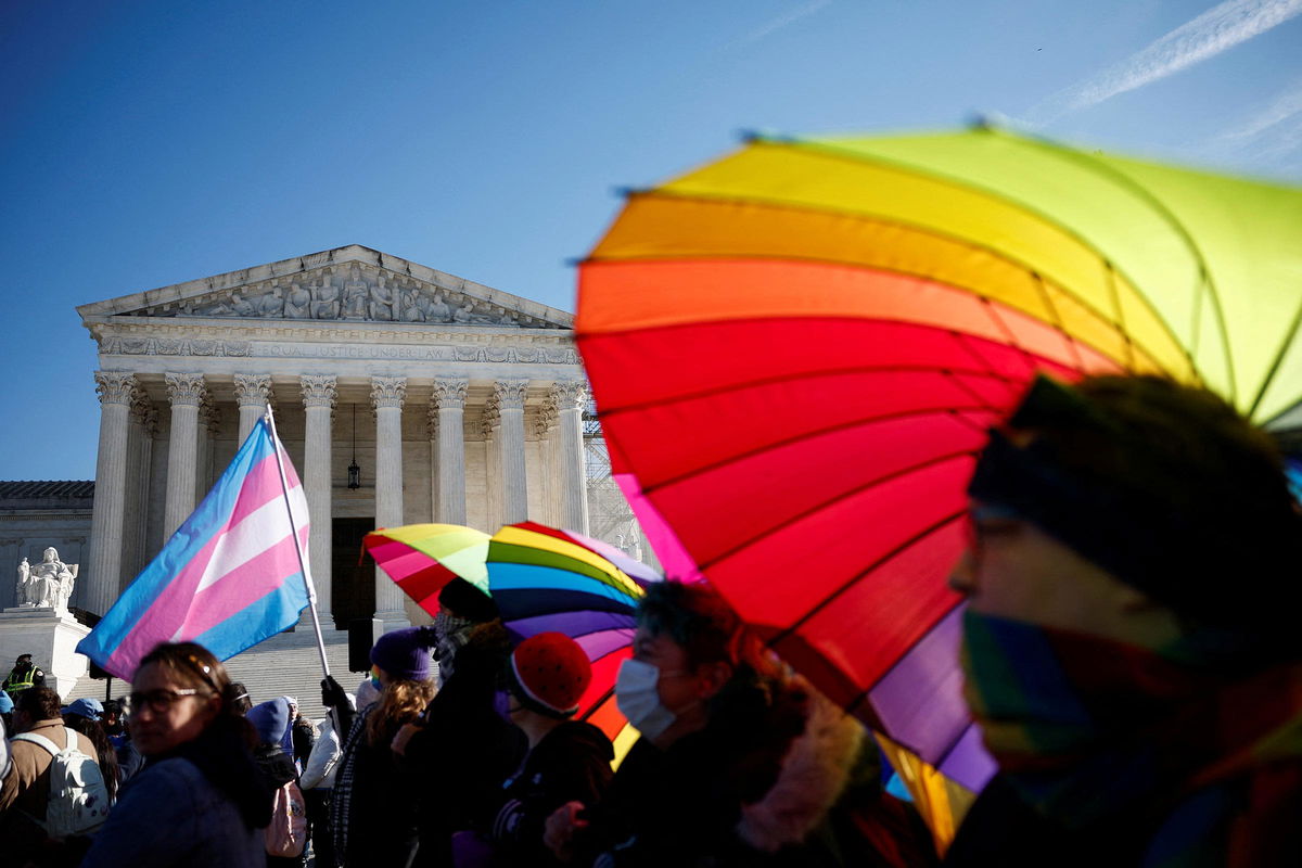 <i>Benoit Tessier/Reuters via CNN Newsource</i><br/>People hold rainbow-colored umbrellas and flags at a demonstration as the US Supreme Court hears arguments over an appeal by President Joe Biden's administration of a lower court's decision upholding a Republican-backed ban in Tennessee on gender-affirming medical care for transgender minors