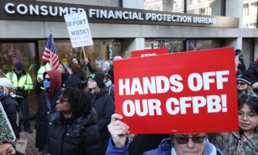 Demonstrators raise signs and posters during a rally outside the Consumer Financial Protection Bureau headquarters in Washington