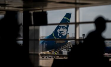 An Alaska Airlines plane past travelers at Ronald Reagan Washington National Airport in Arlington